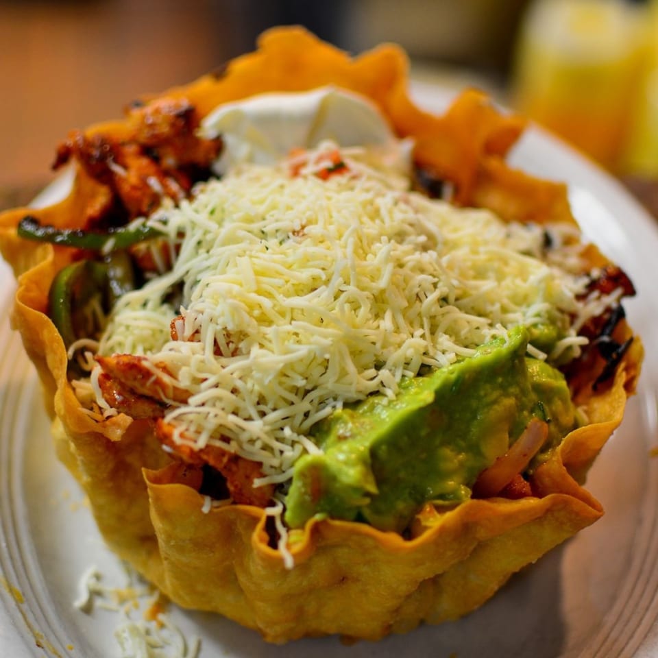 Frida's Mexican Restaurant & Cantina's taco salad in a crispy tortilla bowl, topped with cheese and guacamole.