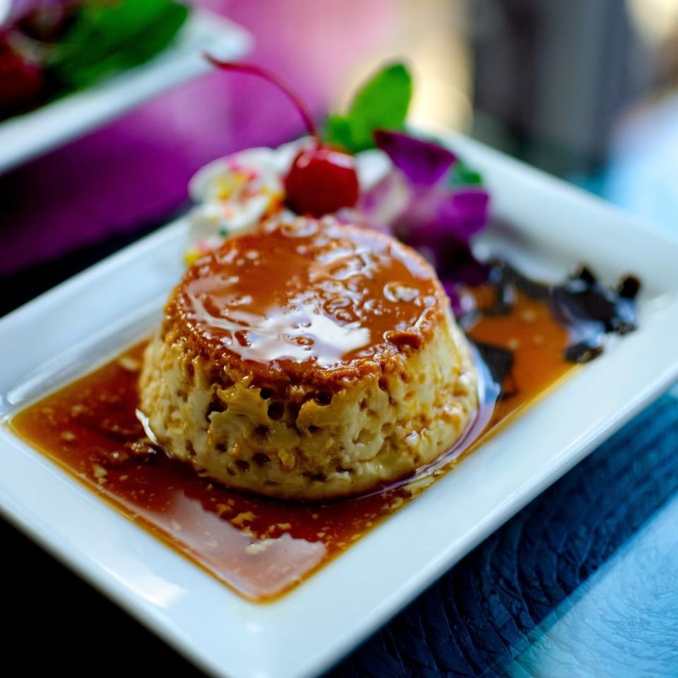 Frida's Mexican Restaurant & Cantina's flan dessert, topped with caramel, a cherry, and an orchid.